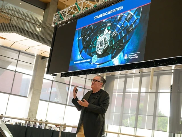 Tomás Díaz de la Rubia conducts a presentation about fusion energy in a glass building